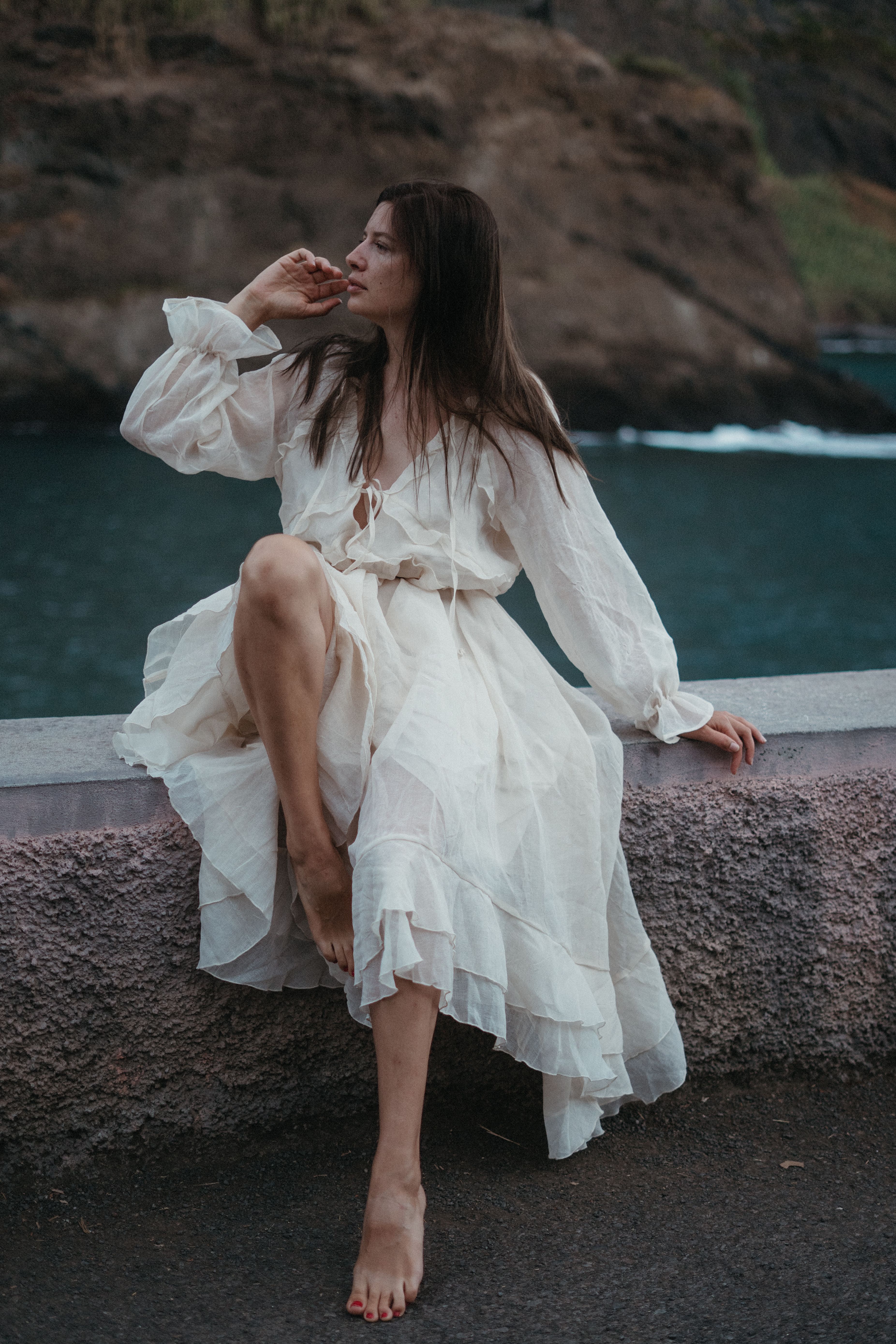 Woman in a white dress sitting by the sea