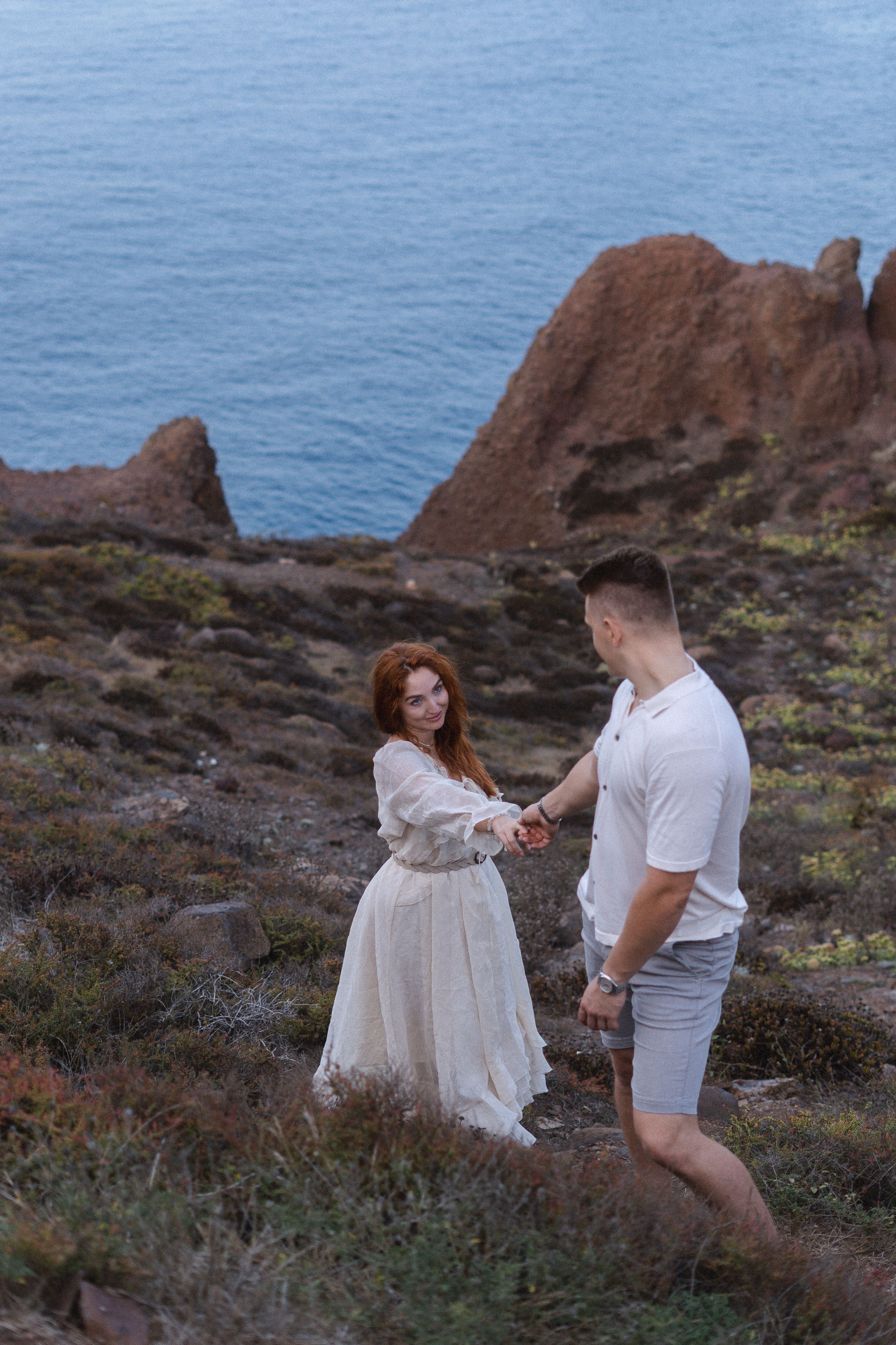 Couple holding hands on a rocky coast