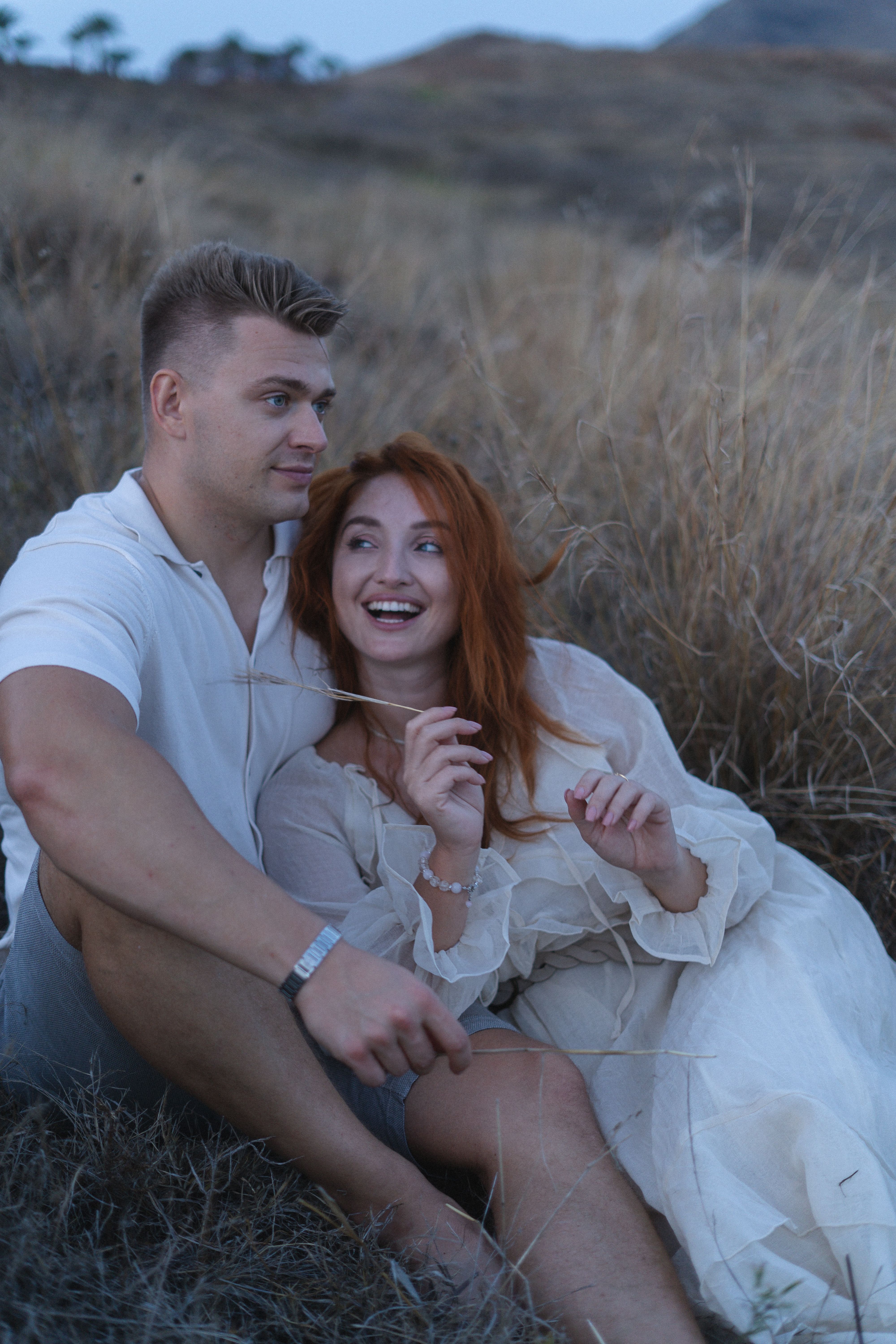 Laughing couple sitting in tall grass