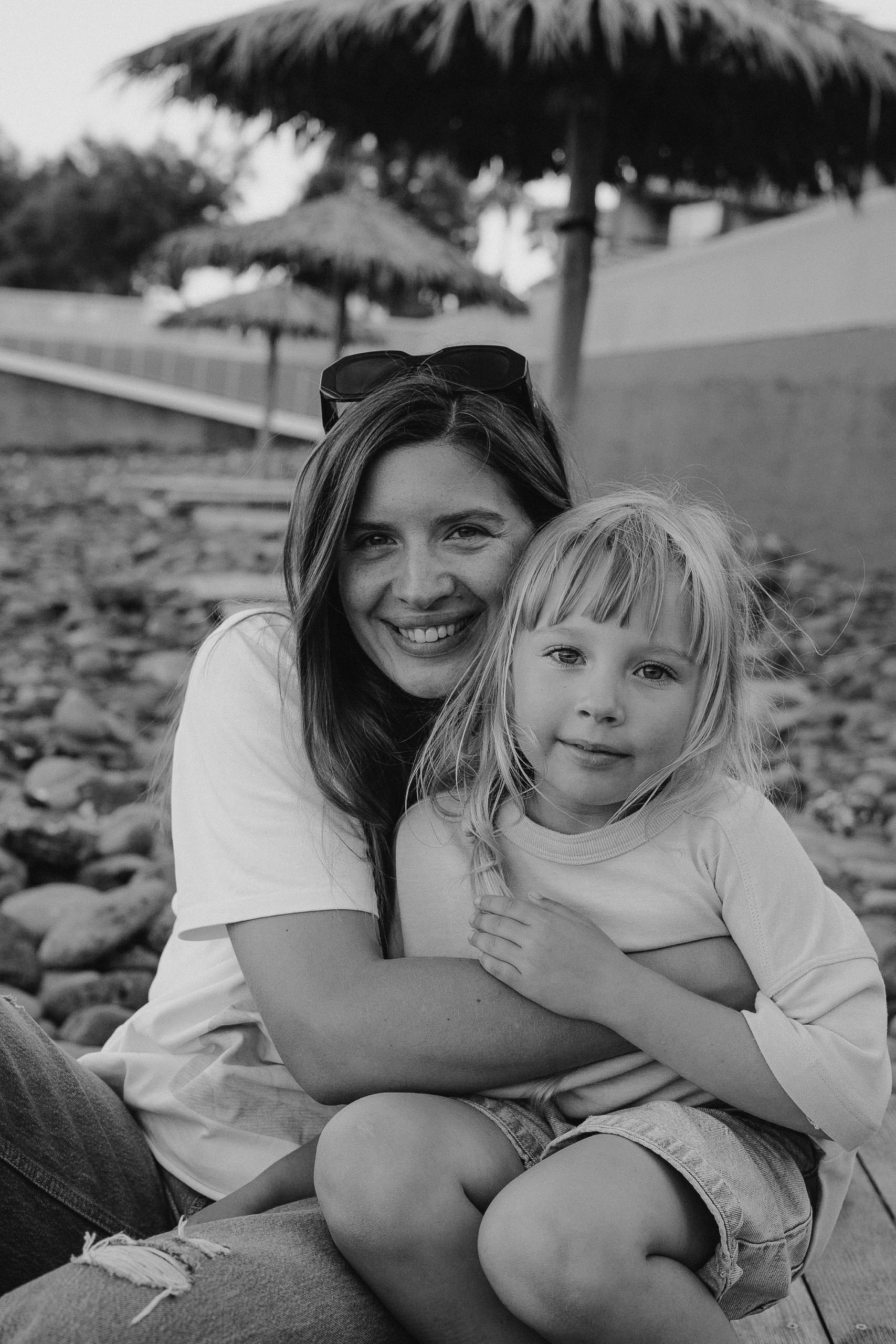 Smiling woman hugs her young daughter in a black-and-white photograph